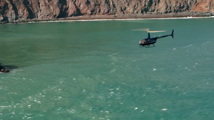 一架直升机沿着海岸线飞行