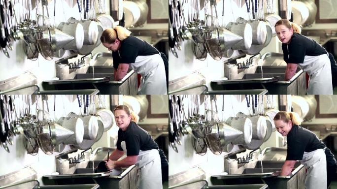 在商业厨房洗碗工作的女性
