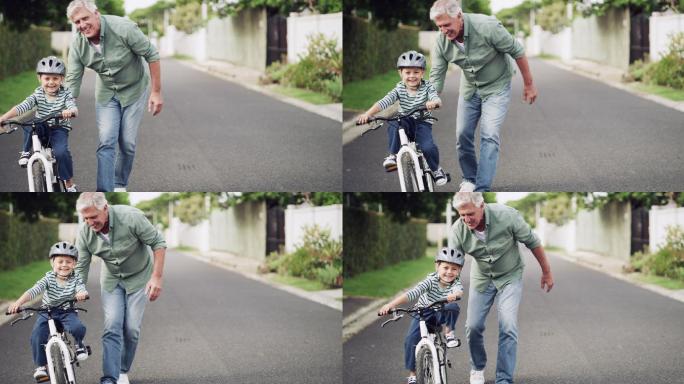 一个可爱的小男孩在户外被祖父教如何骑车