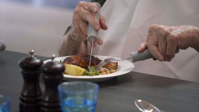 一位患有关节炎的老人用刀叉吃饭