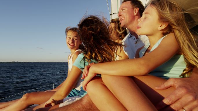 年轻的女孩和父母在游艇上航行