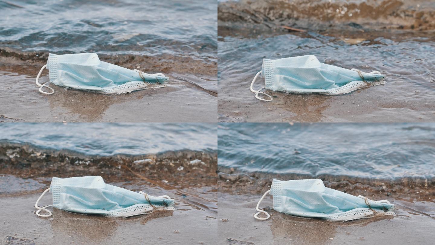 医用口罩躺在被海浪冲刷过的海滩边缘