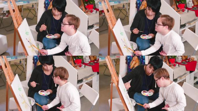 男孩坐在画架旁画画，老师在一旁辅助他