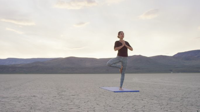 在沙漠做瑜伽姿势的年轻女子