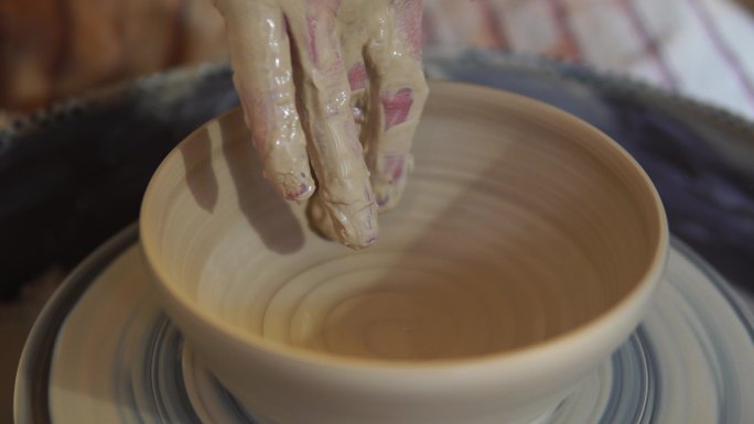 陶工在扭曲的陶轮上制作陶瓷壶。