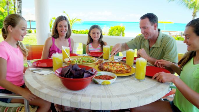 年轻的白人家庭在海滩边户外用餐
