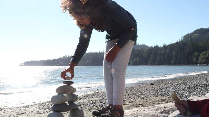 小女孩在海边玩石头搭建
