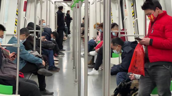 运行地铁车厢里低头玩手机看手机的乘客人群