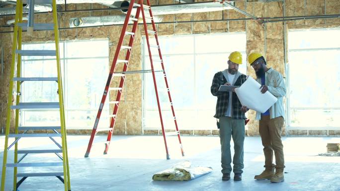 两名建筑工人在一个室内建筑工地讨论