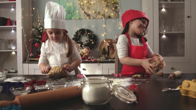 两个可爱的小女孩厨师在揉生面做姜饼饼干