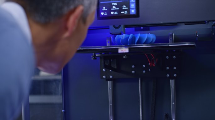 男工程师俯瞰3D打印机内模型的构造
