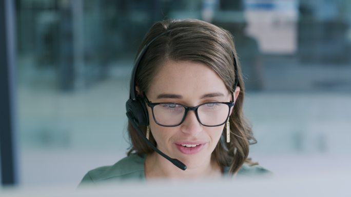 一名年轻女子在现代办公室使用耳机和电脑