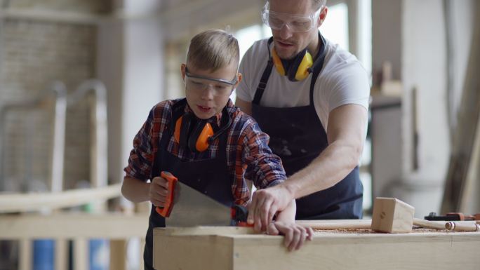 木匠教儿子如何用手锯切割木板的中镜头