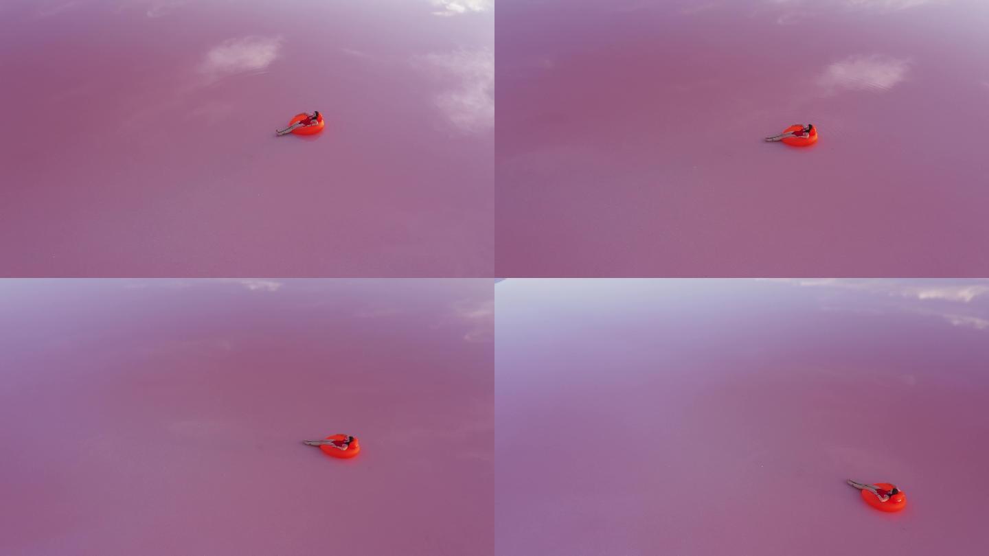 粉色盐湖上一名女子躺在充气环上的鸟瞰图
