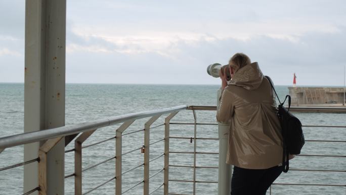 女人用双筒望远镜看海
