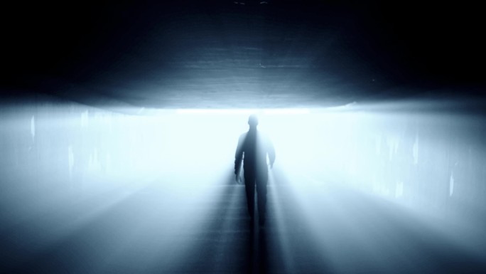 一个人在隧道里走向强光的剪影。