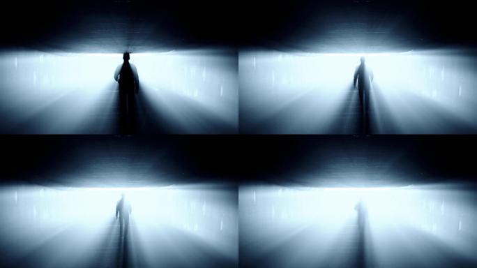 一个人在隧道里走向强光的剪影。