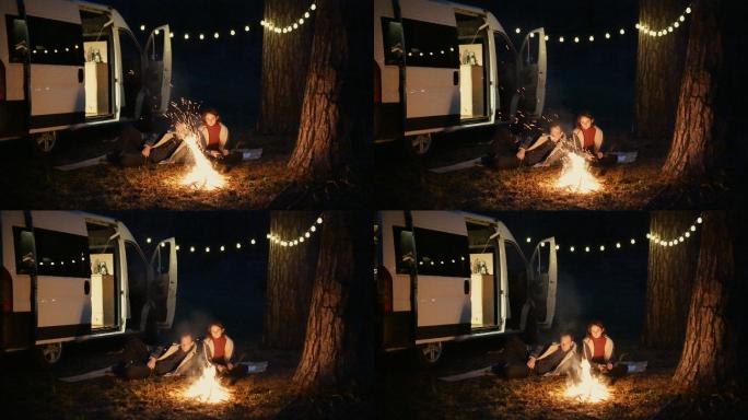男女坐在篝火旁野营夫妻情侣房车自驾游