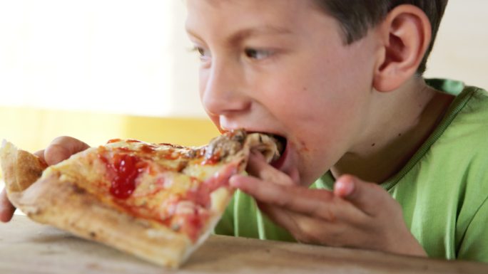 男孩正在吃一片披萨