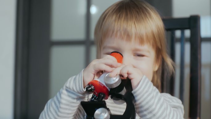使用玩具婴儿显微镜的可爱的男孩