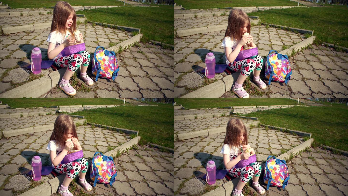 金发小女孩在公园里吃午饭。