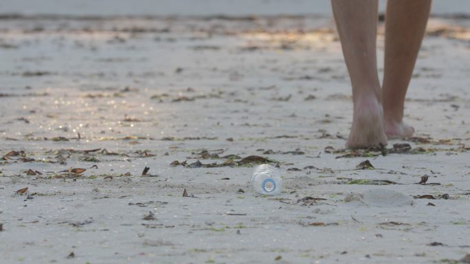 男子将塑料瓶扔到海滩上，女子将其捡起来