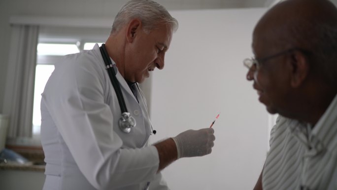 医生给一位老年患者注射疫苗