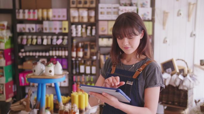 在熟食店使用数字平板电脑的年轻熟食店老板