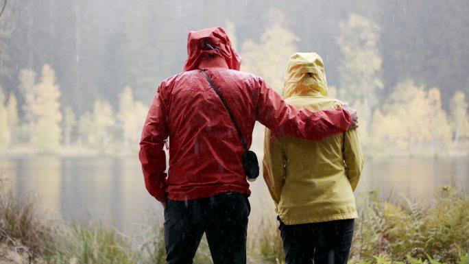 雨天，男人和女人在湖边欣赏风景