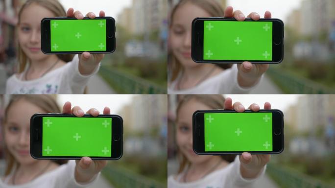 女孩向摄像机展示了一部带有绿色屏幕的手机