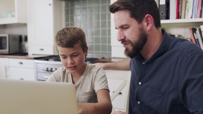 一对父子在家里一起使用笔记本电脑