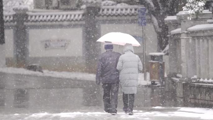 下雪天老年夫妻手挽手走路背影