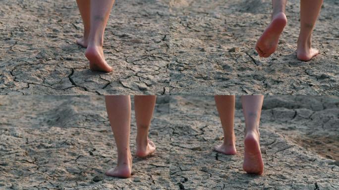 女孩赤脚在干旱开裂的土地上行走的脚步