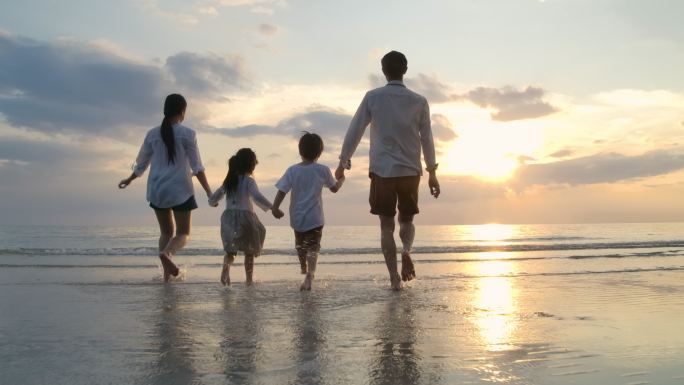 日落时在海滩上奔跑的一家人