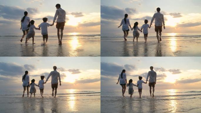 日落时在海滩上奔跑的一家人