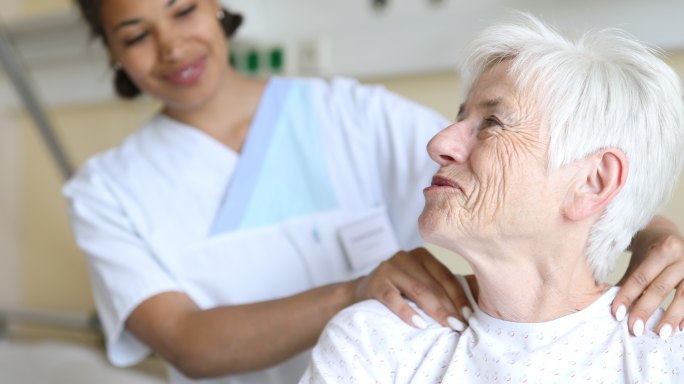 高级女患者在病房接受物理治疗师的肩部按摩