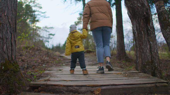 小男孩和妈妈手拉手在公园里散步