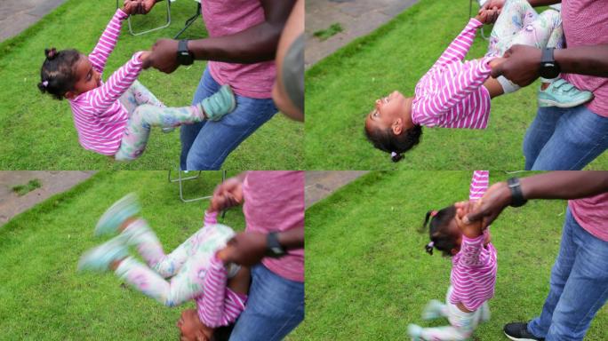 一个小女孩在户外玩耍时爬上她的父亲