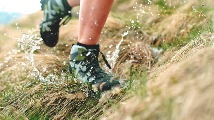 穿着登山靴的女人在潮湿的草地上奔跑