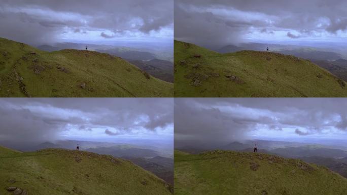 山上的徒步旅行者高峰巅峰高处操控无人机眺