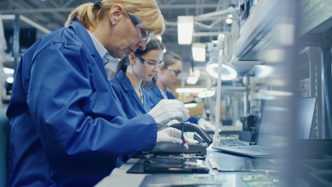 电子工厂女工人正在用螺丝刀组装智能手机