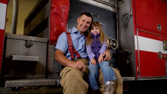 坐在消防车上的消防员和年轻女孩