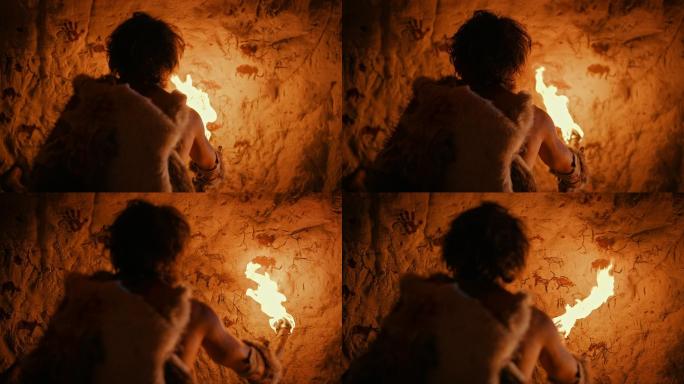 穿着兽皮的原始穴居人拿着火把看墙上的画。