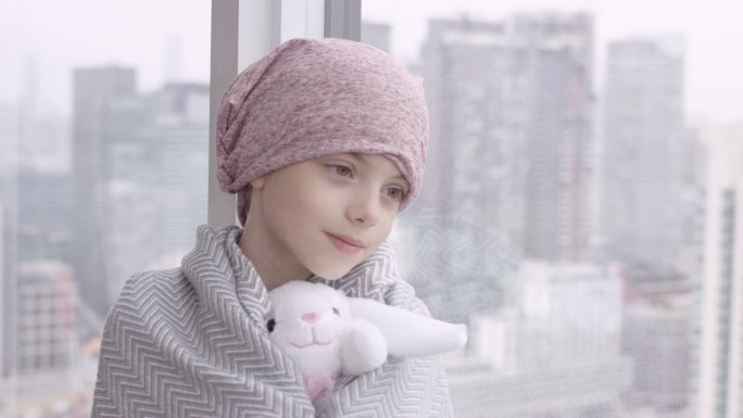 患癌症的快乐女孩靠在窗户上