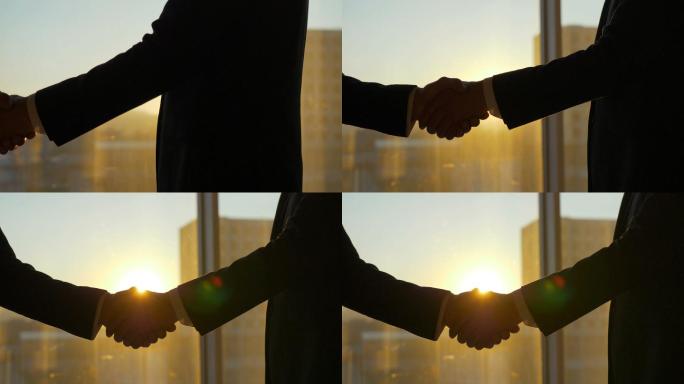 两人在日落的背景下握手。