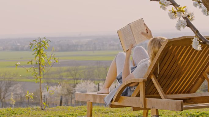 年轻女子躺椅上放松和看书