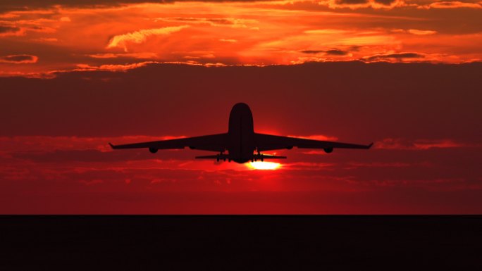大型客机在橙色夕阳下起飞的剪影