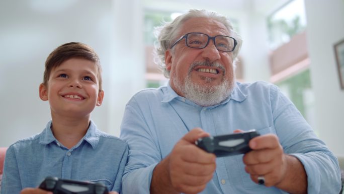 快乐的孙子和爷爷在客厅玩电子游戏的肖像