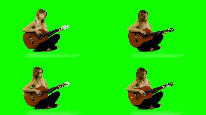 年轻女子在绿屏背景上弹吉他。