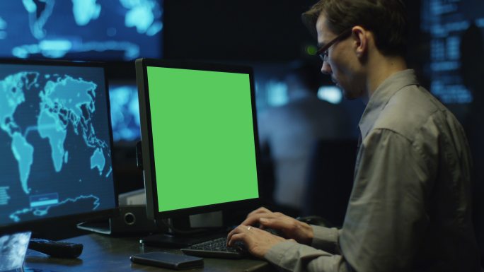 编程人员在系统控制室的绿屏计算机上工作。